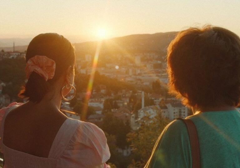 Two women facing a sunlit valley
