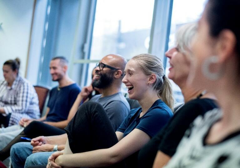 A group of teachers sit in a room laughing. 