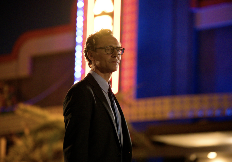 Tom Hiddleston stands in front of a vintage cinema