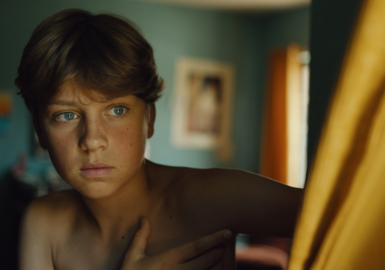A young boy behind a curtain.