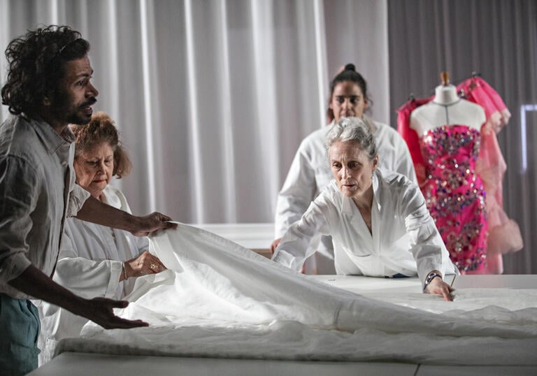 Four people gather around a large piece of white fabric.