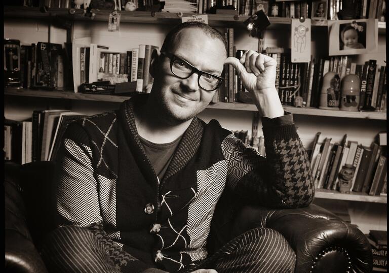 Black and white portrait of Cory Doctorow sitting in an armchair