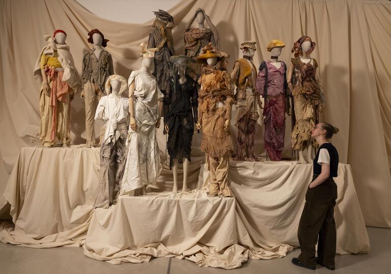 A woman looks at a collection of earth-toned outfits by designer Paolo Carzana.