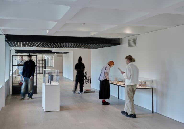 A photo looking down the gallery, with people looking at artworks in the exhibition.
