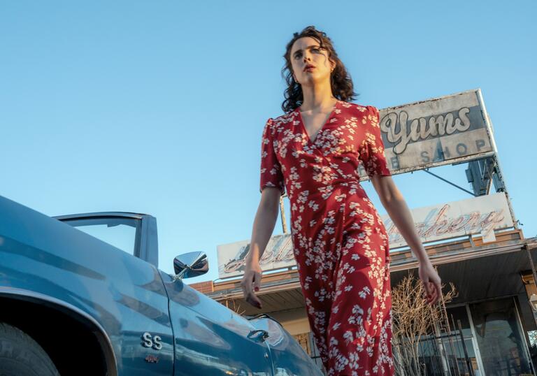 Margaret Qualley strides determinedly in a red floral dress