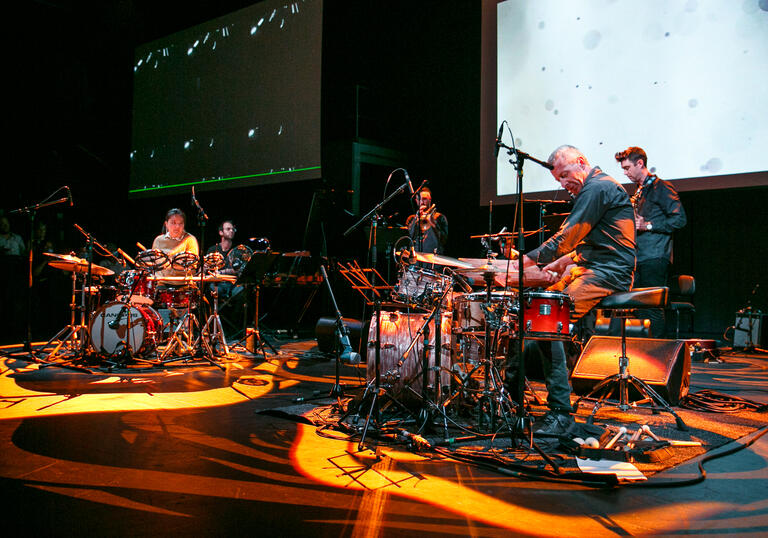 An image of two drummers playing on stage 