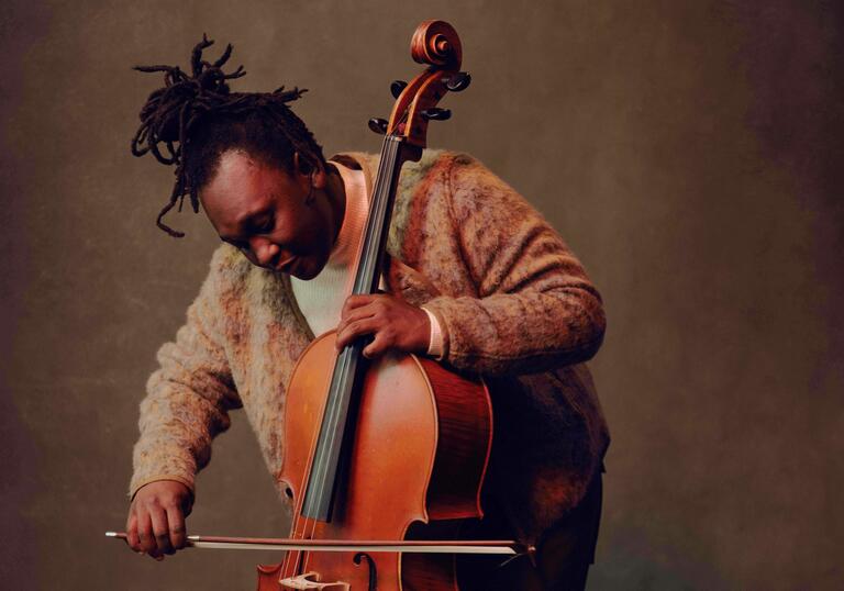 Abel standing and playing the cello