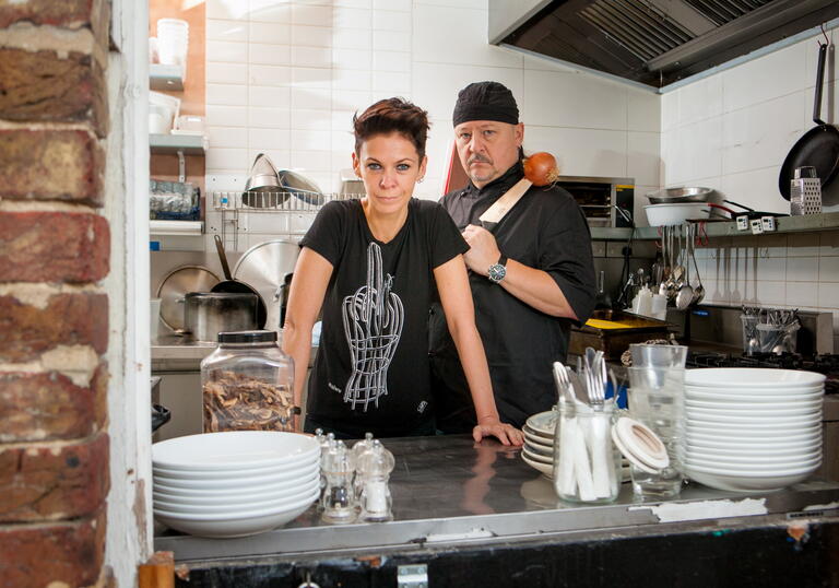 Belarus Free Theatre's co artistic directors stand in a kitchen and look at the camera. 