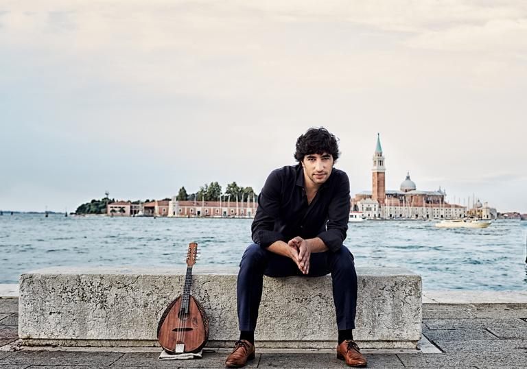 Photo of man sitting on a concrete bench by the sea