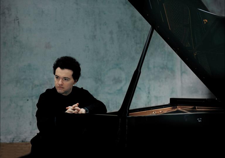 A colour photograph of Evgeny Kissin by a piano