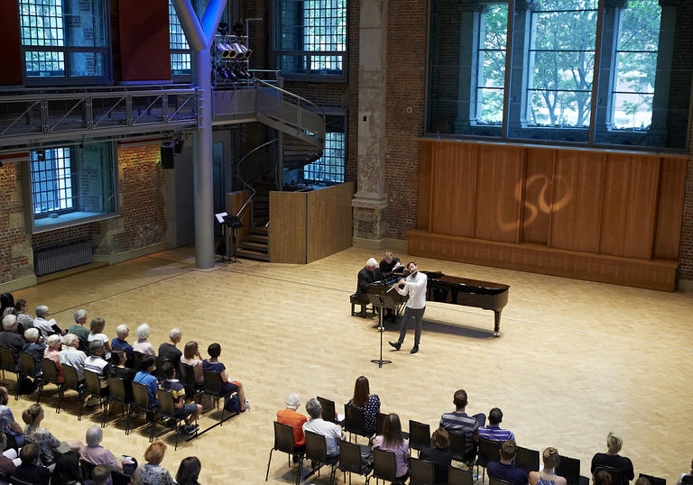 Photo of a man playing the piano on stage in front of an audience