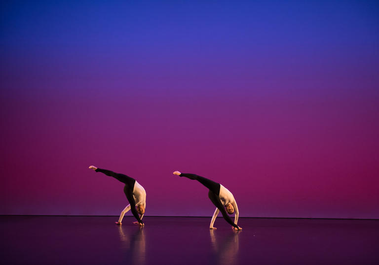 A coloured image showing two dancers from the Michael Clark Company against a blue and pink background