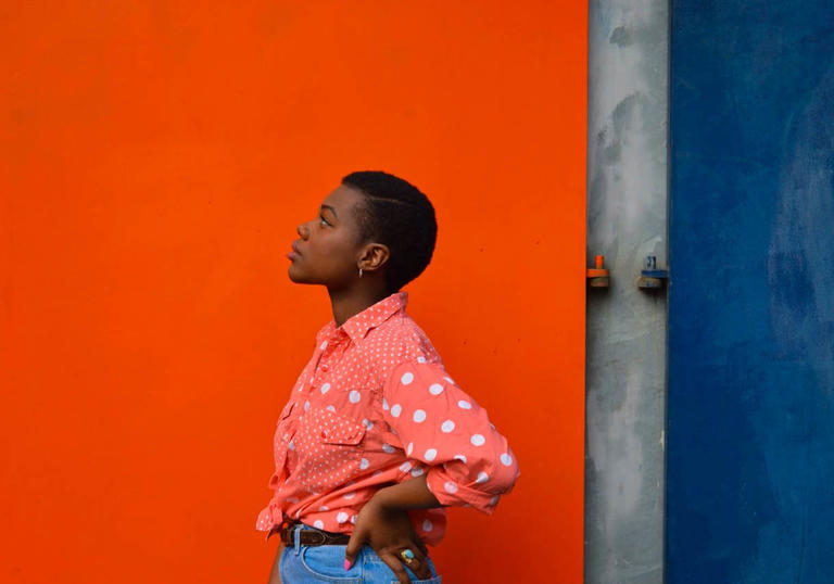Young woman standing in front of a red wall