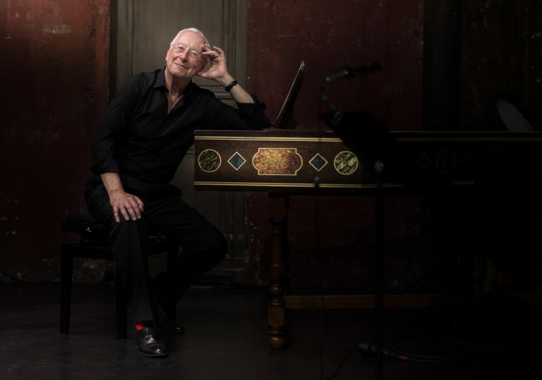 Image of conductor William Christie by a harpsichord