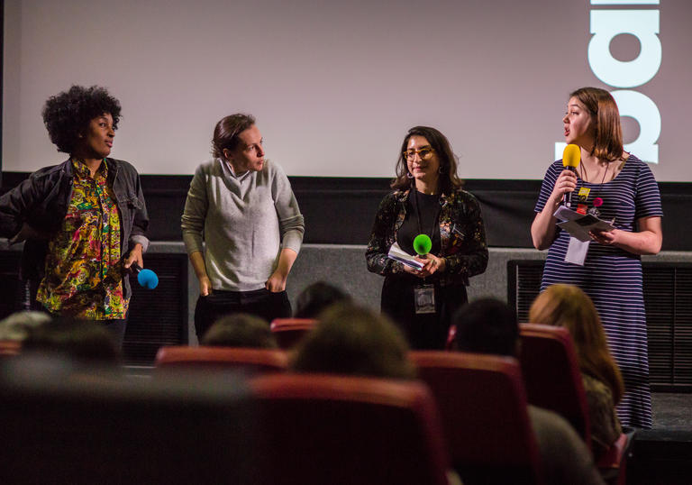 Four panel members stand before a screen