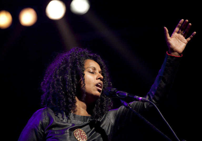 Susheela Raman singing and raising her hand to the sky