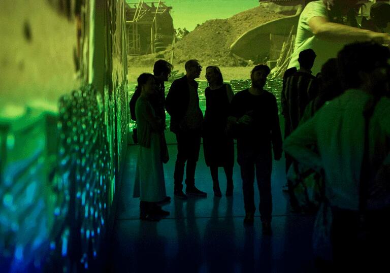 Photo of young people in a gallery by large film projections