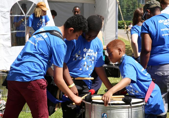 three people playing a metal drum