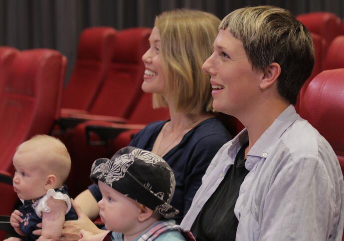 Photo of two women with babies watching a film in the Barbican cinema