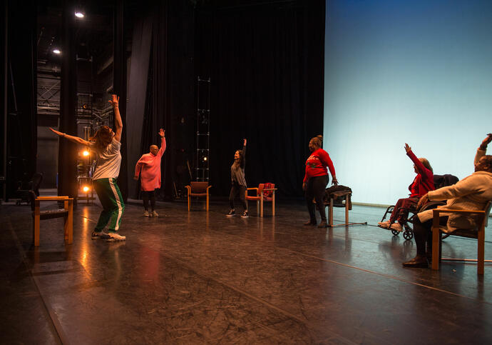 A group of people sit on chairs on the Barbican stage