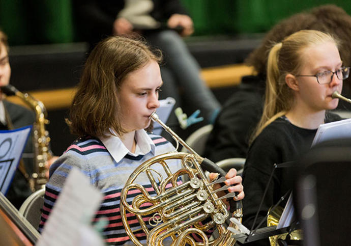 Girl playing french horn in orchestra