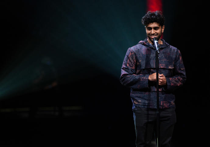 image of artist Azan standing behind a microphone