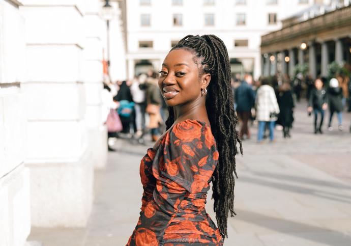 black female in black and red dress and hair tied up in braids