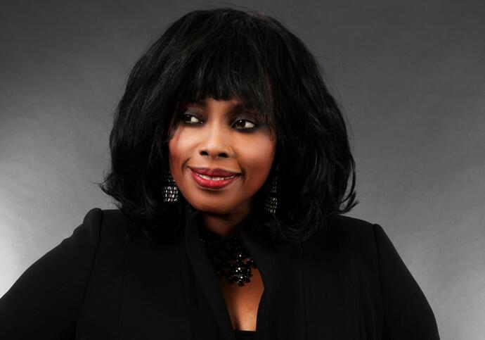 Ruby is wearing a black blouse and in front a grey background.