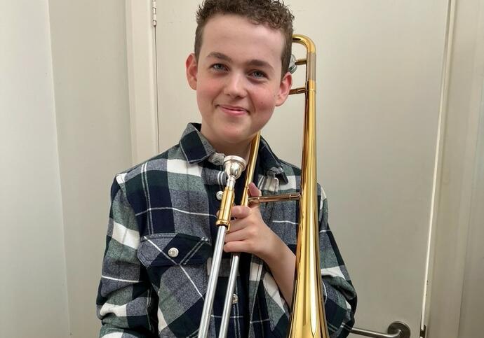 Image of Jonah, wearing checked shirt and holding trombone