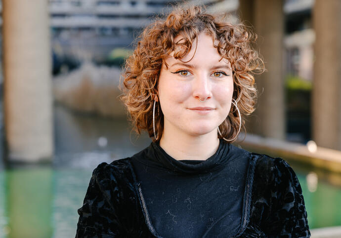 Image of Maisie smiling, wearing black dress and has red curly hair