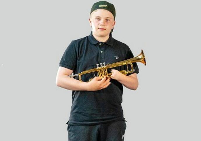 Image of Sam in black top, shorts and cap, holding a trumpet