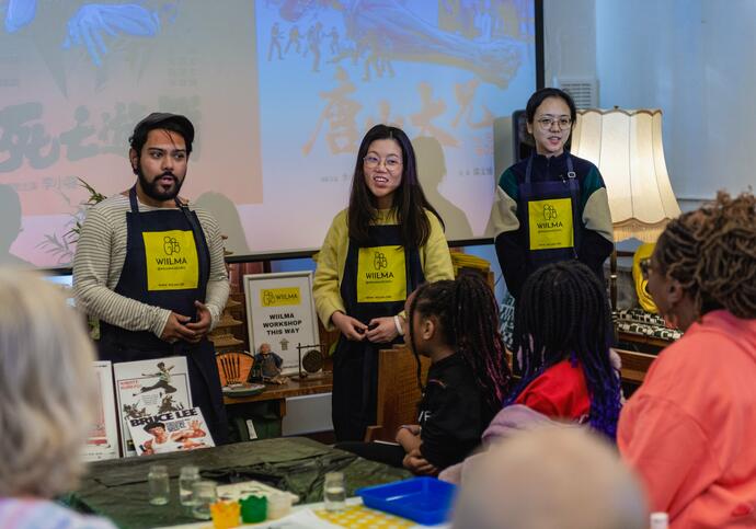 3 people standing at the front in aprons with 'WIILMA' written on them