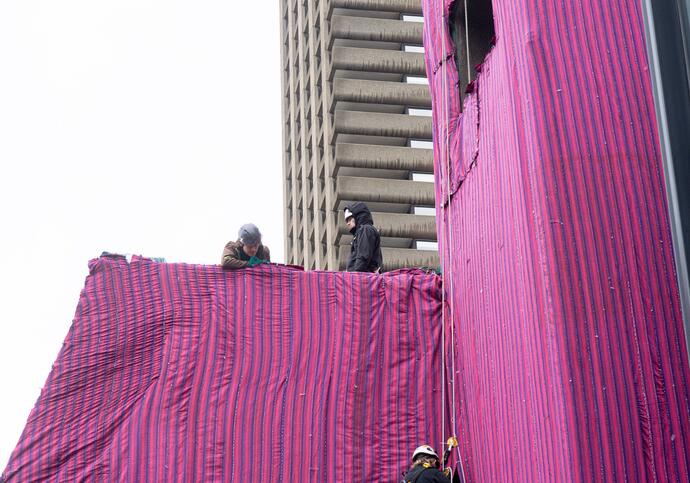 riggers on top of the lakeside terrace attach fabric to the building