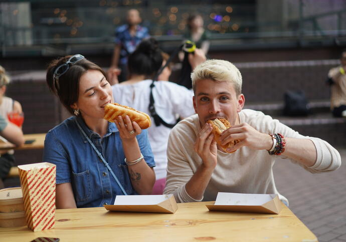 Two influencers munch a hot dog