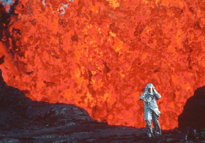 A woman stands in front of an exploding volcano.