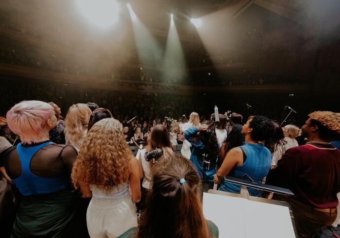 An ensemble standing on stage looking out into the audience