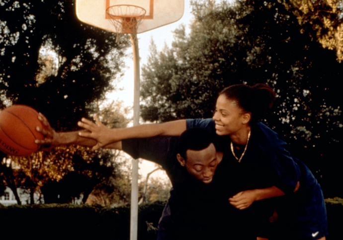 A man and a woman play basketball on an outdoor court.
