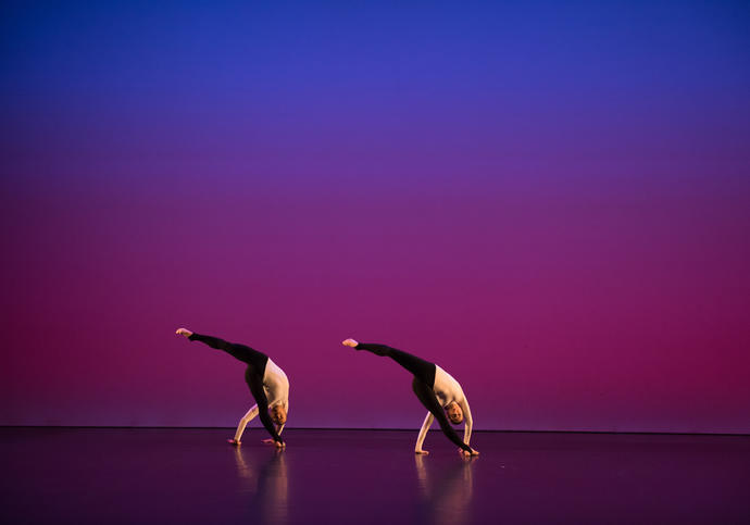A coloured image showing two dancers from the Michael Clark Company against a blue and pink background