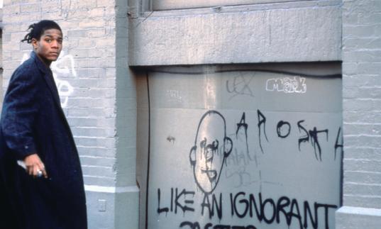 Photo of Basquiat standing by graffiti