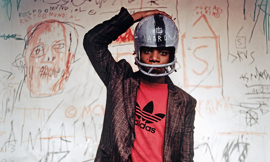 Photo of Basquiat wearing an Adidas tshirt, suit and football helmet