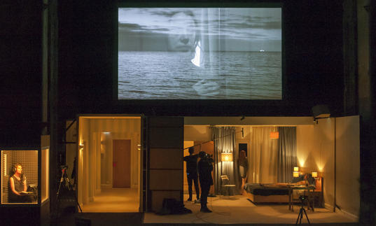 A screen on the top half of the image showing a woman's face and the sea. Below is a woman in a bedroom film set and a narrator in a recording box.