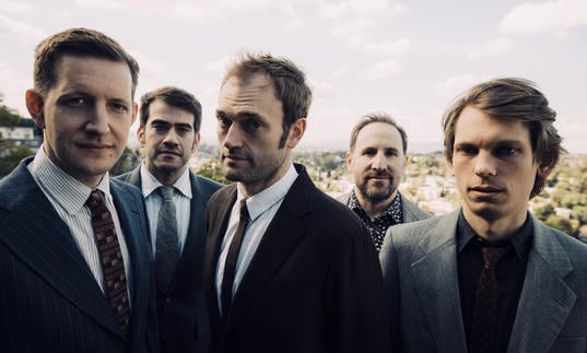 Punch Brothers in suits standing in a field