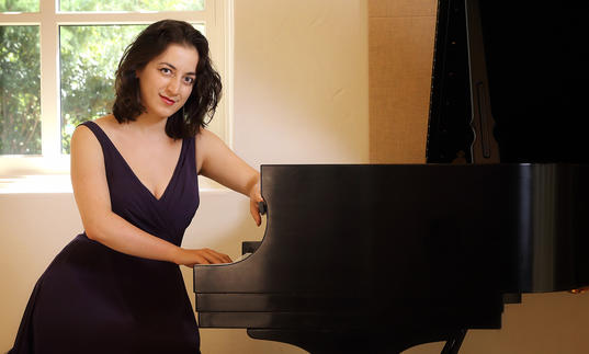 Pianist Sophiko Simsive sits by a piano