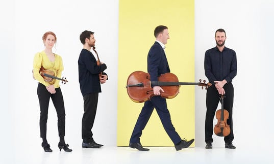 Heath String Quartet on white and yellow background holding instruments
