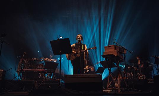 Karine Polwart singing and playing an acoustic guitar on stage