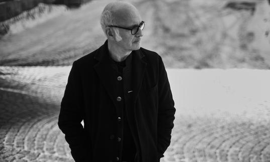 Ludovico Einaudi standing outside with his hands in his pockets, looking to his left.