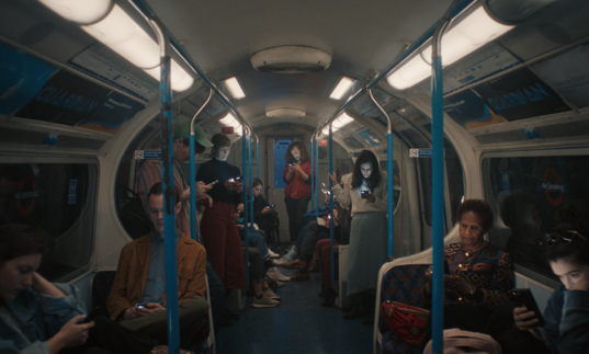 Group of people on underground train all looking at their phones