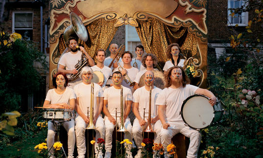 Hackney Colliery Band sat in two lines with their instruments