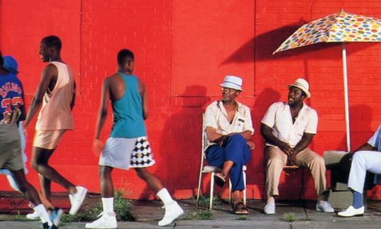 men walking in front of red wall
