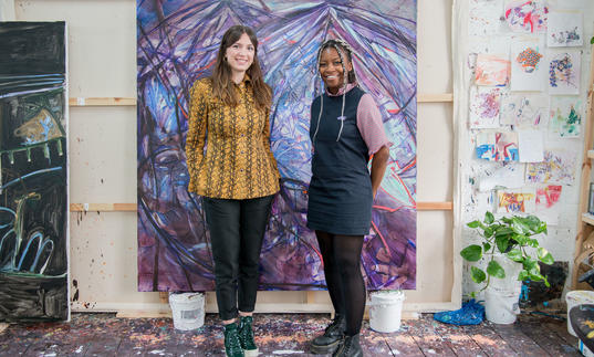 Two women standing in front of a purple painting